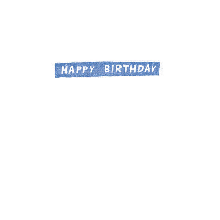 A rectangular blue sticker or label with the words 'HAPPY BIRTHDAY' in white capital letters