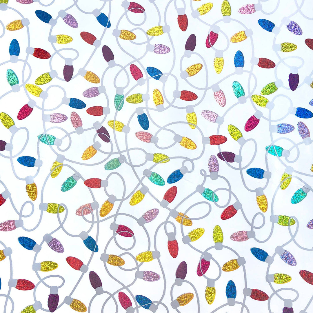 Colorful Christmas lights strung together and arranged randomly on a white background