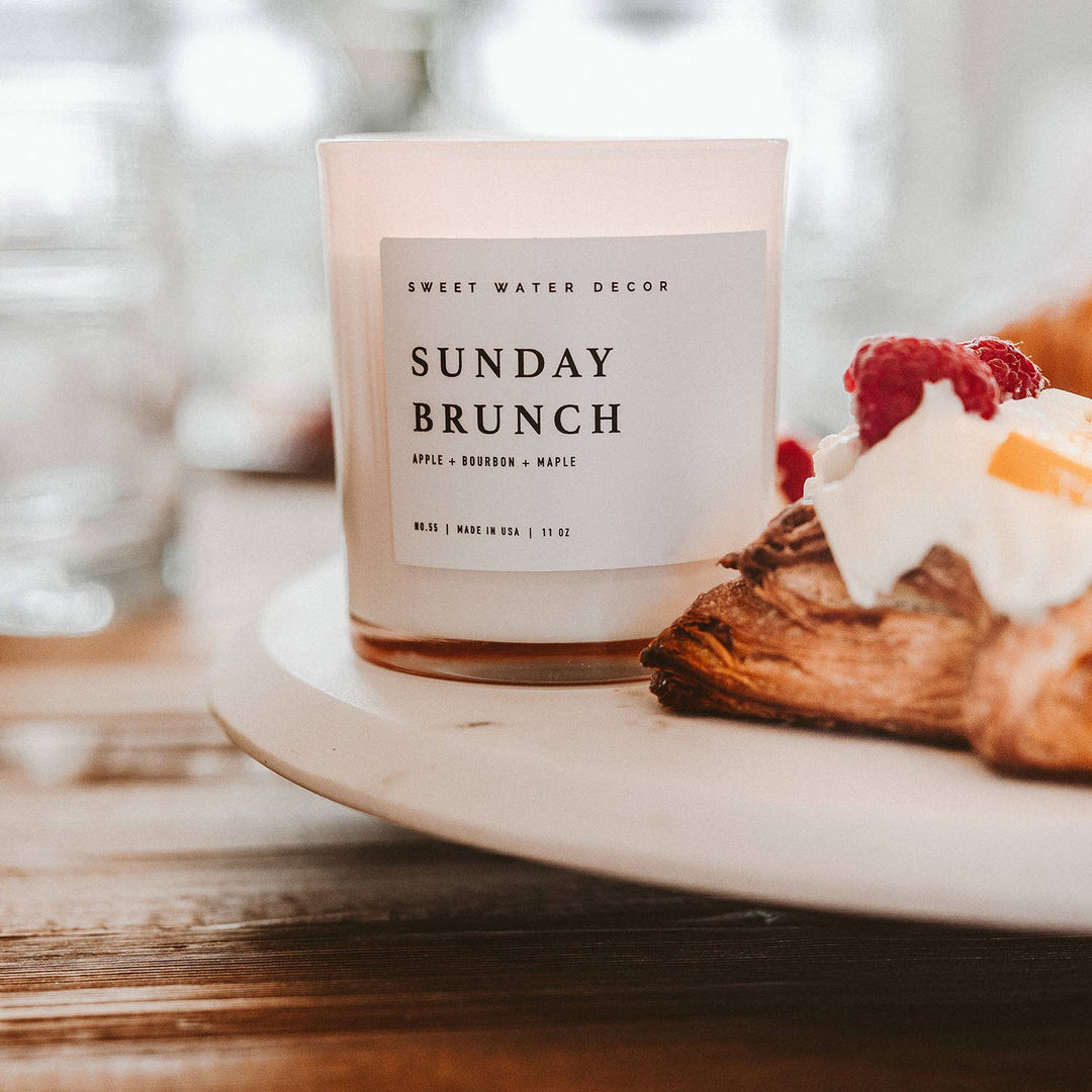 Scented soy candle in white matte glass container. Label is Sunday Brunch Apple / Bourbon / Maple