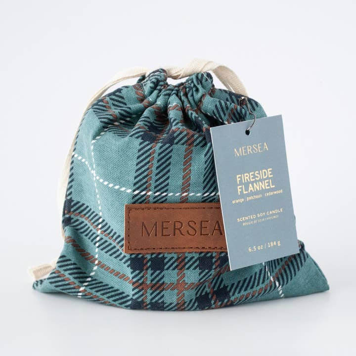 A teal and navy plaid drawstring pouch with a brown leather patch embossed with 'MERSEA' and a gray hanging tag that reads 'MERSEA FIRESIDE FLANNEL'.