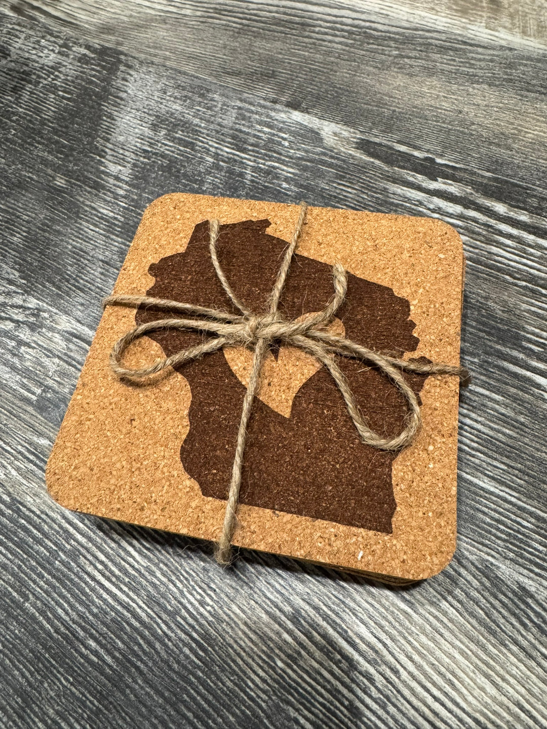 Cork coasters with a silhouette of Wisconsin and a heart bound with twine.