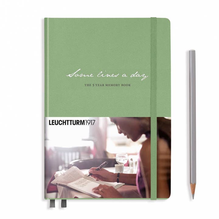 A sage hardcover memory book from Leuchtturm1917 with an elastic closure and a printed cover wrapper, shown alongside a matching sage Leuchtturm1917 pencil.