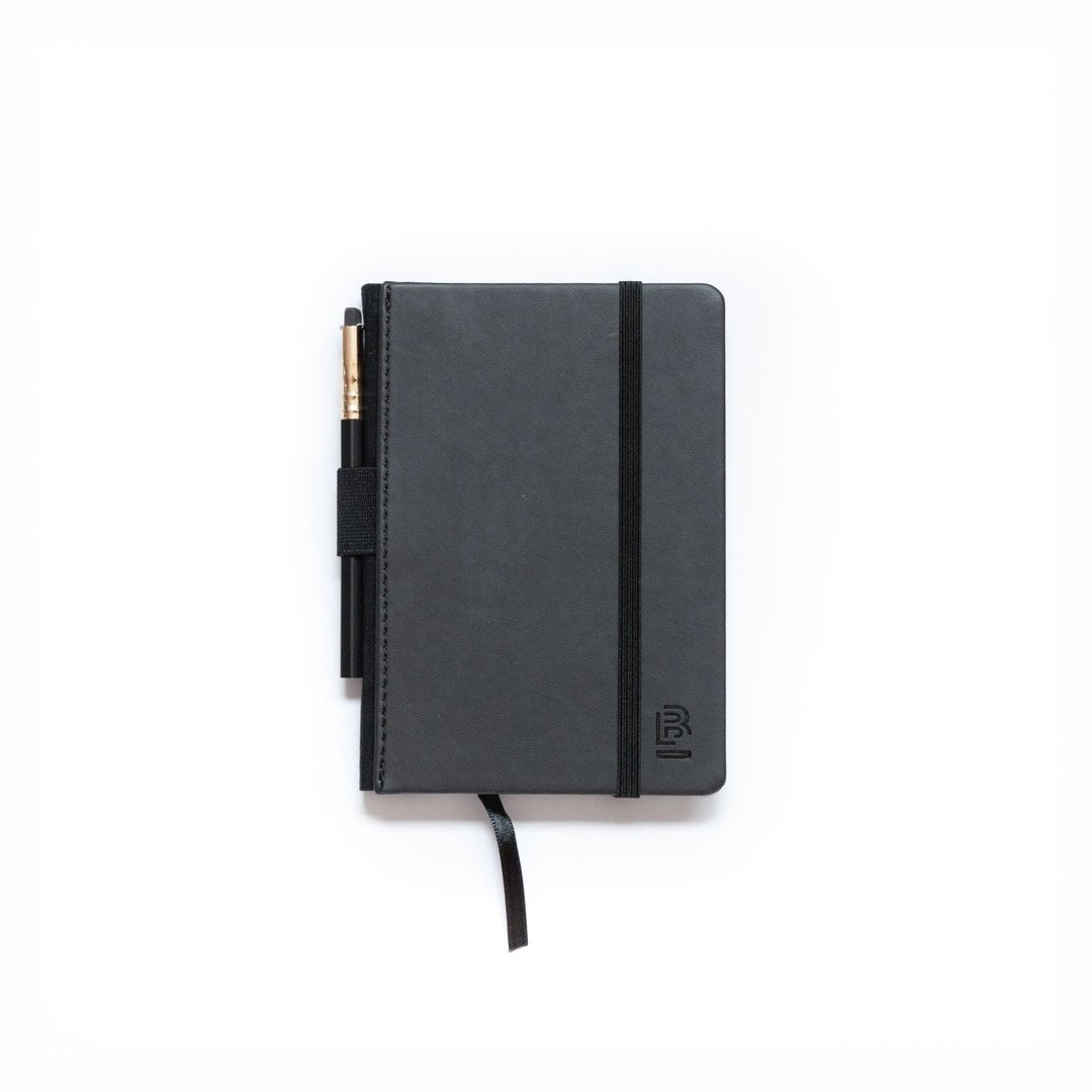 Black notebook with a pencil in holder and elastic closure band.