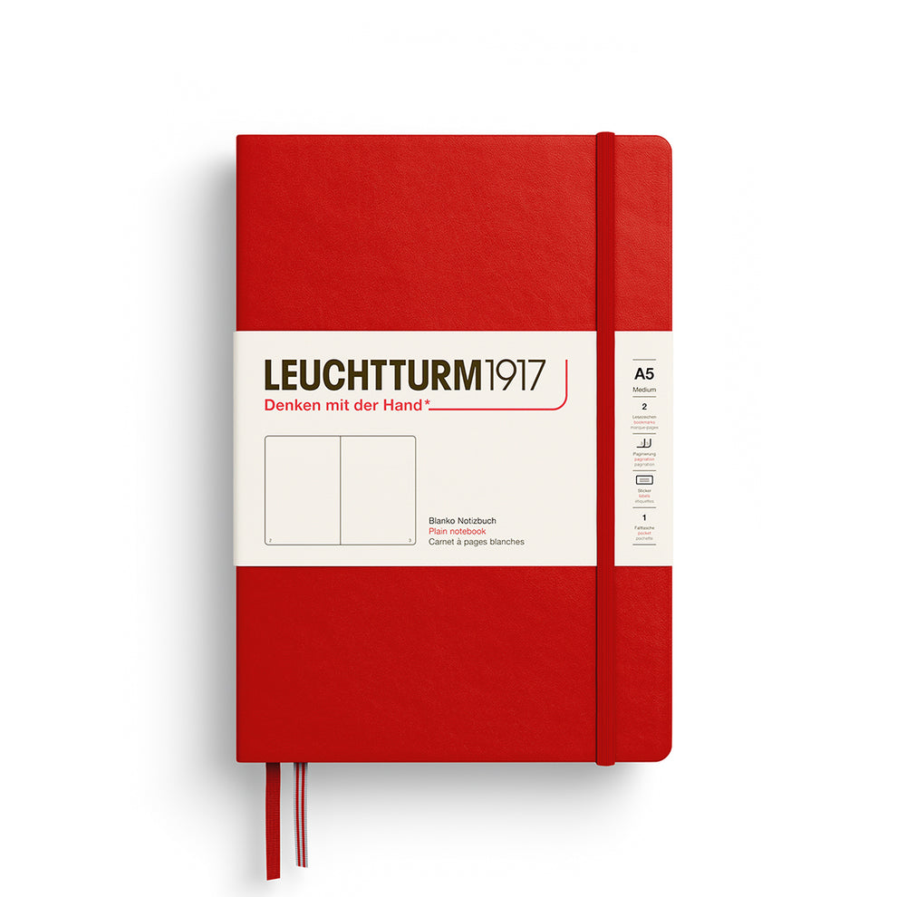 A Leuchtturm1917 A5 hardcover plain page notebook in red with a white label on the front, shown closed with an elastic closure and ribbon bookmark. 