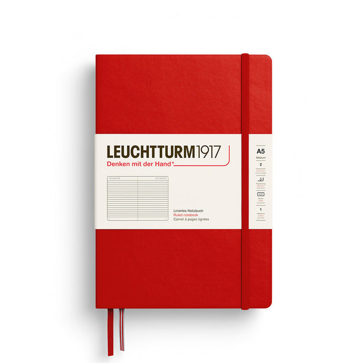 A Leuchtturm1917 A5 hardcover ruled page notebook in red with a white label on the front, shown closed with an elastic closure and ribbon bookmark. 