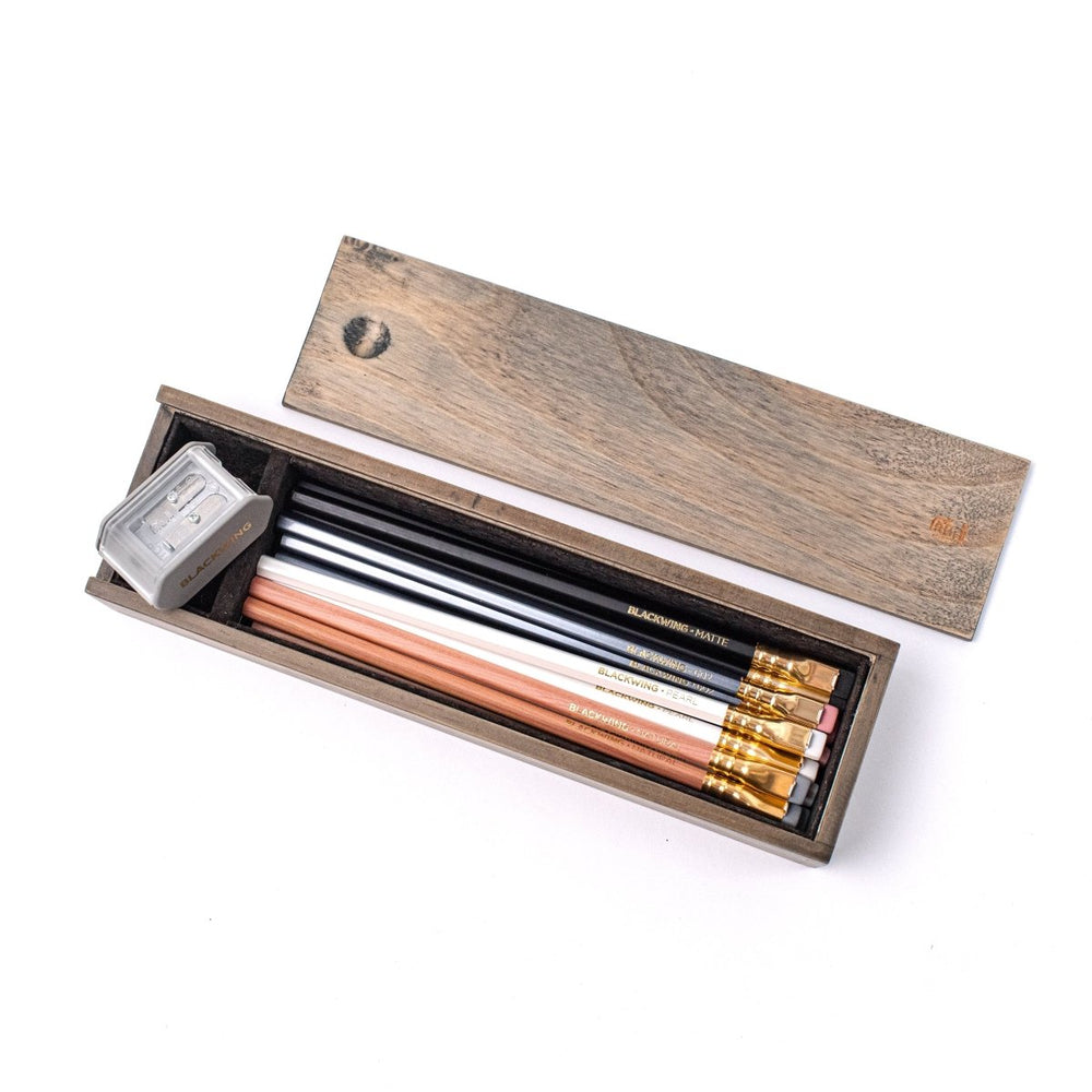 Set of branded pencils and sharpener in a rustic wooden box with the top fully removed.