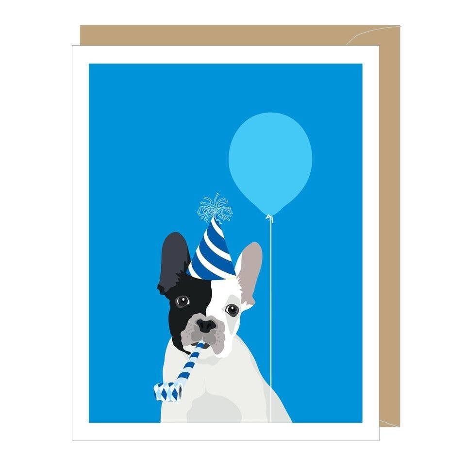 White dog with half black face, wearing a blue and white striped party hat, blowing a noise maker, and holding a blue balloon.