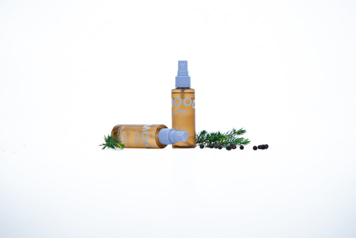 two spray bottles, one on its side and one upright, with pine sprigs