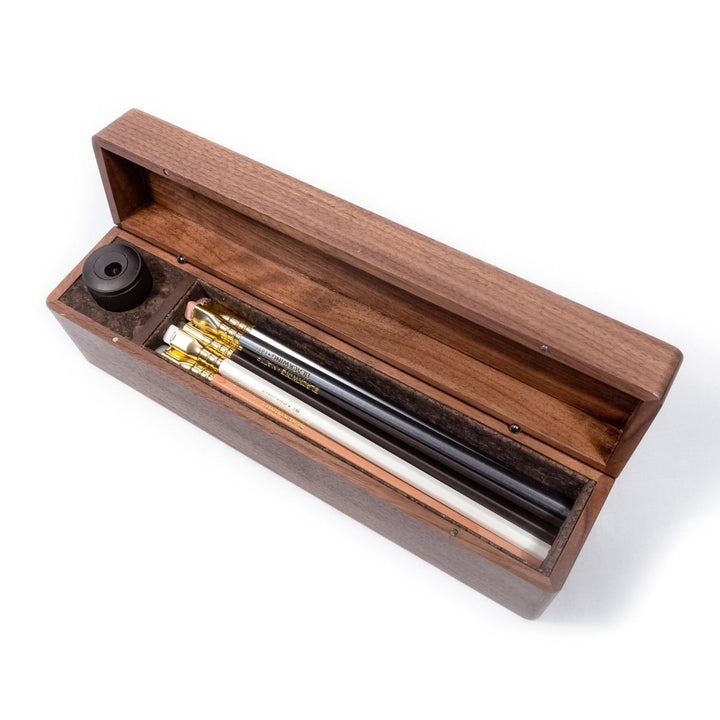 Cork lined walnut case with lid hinged open showing a set of pencils and sharpener.