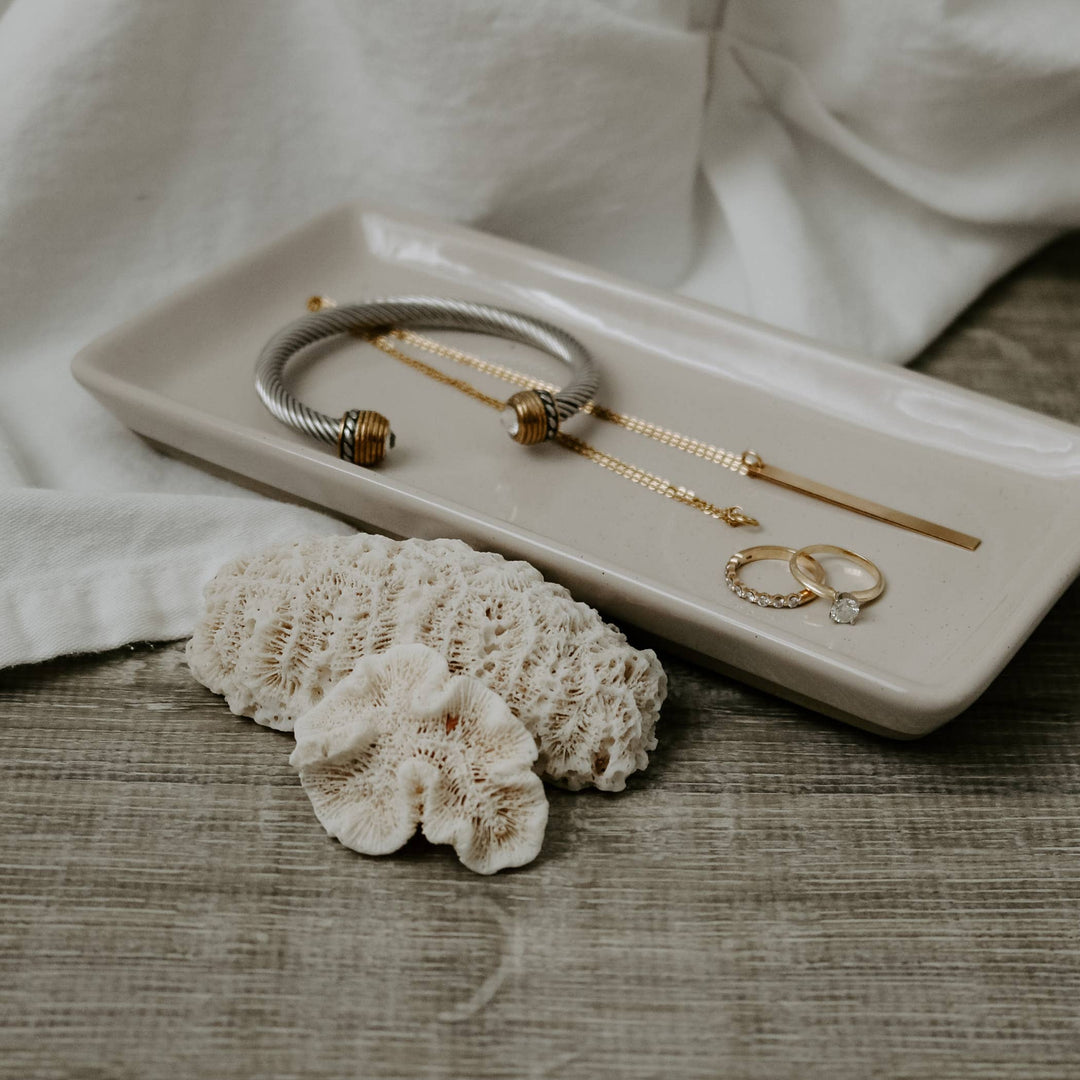 White matte stoneware tray holding jewelry.